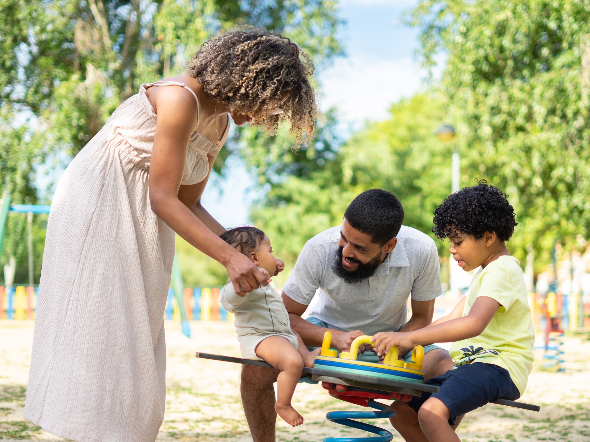 Latin family playing together in a playground with their children, a boy and a baby